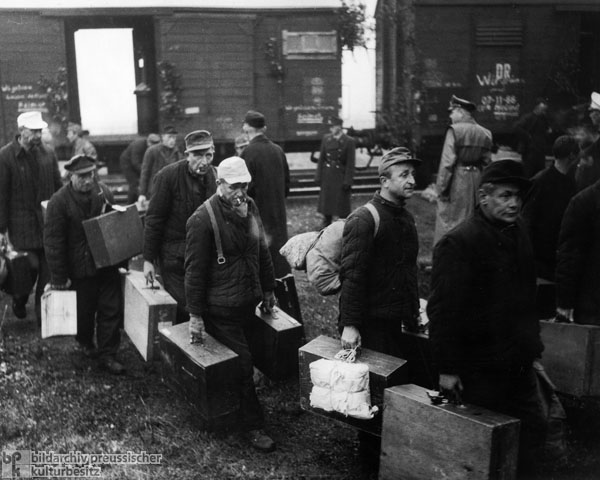 Eine Gruppe von Heimkehrern aus der Sowjetunion verlässt auf dem Grenzbahnhof Herleshausen (Hesse) die für den Transport genutzten Güterwagen (1. Oktober 1955)